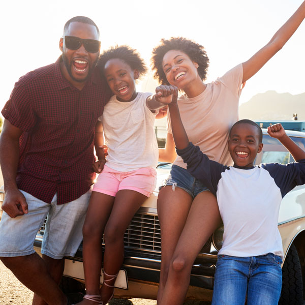 family of four smiling on road trip